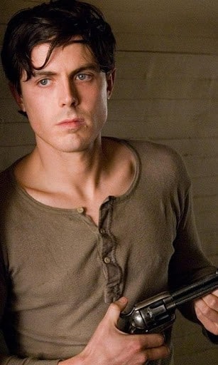 actor nominee casey affleck looking sexing in a tan shirt and holding a gun