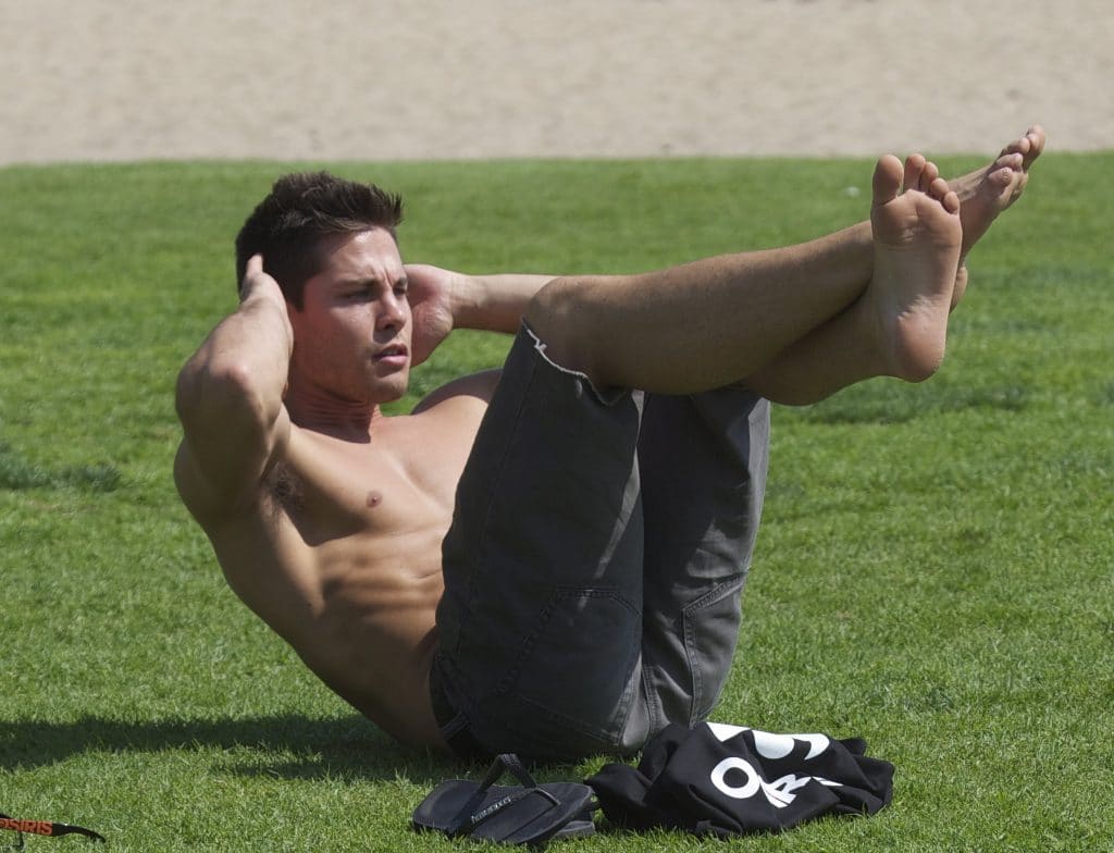 Dean Geyer shirtless doing crunches in the grass